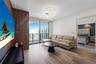 Vertical wood-slat accent wall, floor-to-ceiling glass windows, wood-finish flooring, and circular multi-ring LED flush-mount lighting
