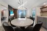 Modern living space featuring floor-to-ceiling windows, wood-panel accent wall, built-in wet bar with shelving, integrated recessed lighting, and a li