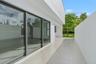 Modern exterior patio featuring smooth stucco walls, large-format tile flooring, oversized glass sliding doors, and dark-framed window casing