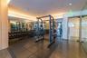 Fitness center featuring rubber flooring, recessed cove lighting, full-wall mirrors, wood-finish wall panels, and glass-entry doors