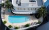 Rooftop terrace featuring an in-ground swimming pool, separate spa, tiled decking, and mature palm trees