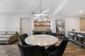 Built-in wet bar featuring stone-surface countertops, custom cabinetry, integrated wine refrigeration, and floating wood shelving, illuminated by a ge