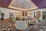 Geometric patterned tile flooring, coffered ceiling with hand-painted artistic detail, recessed perimeter lighting, and arched doorways with wood-pane