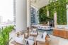Covered terrace featuring stone tile flooring, a multi-story living wall, and large structural support columns