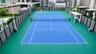 Rooftop sports court featuring a dual-purpose tennis and basketball surface, perimeter security fencing, and shaded seating structures