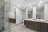 Floating double vanity with rectangular vessel sinks, floor-to-ceiling tiled glass-enclosed shower, stone-finish flooring, and dual wall-mounted mirro