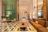 Grand lobby featuring expansive ceiling heights, geometric stone flooring, floor-to-ceiling decorative metal screening, mirrored wall panels, and rece