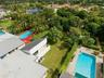 Aerial perspective of a multi-section residential structure featuring a shingle roof and a spacious backyard with mature landscaping