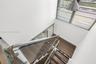 Staircase featuring wood-finish treads, glass panel railing, metallic handrails, and a modern industrial-style pendant light