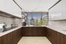 Kitchen featuring two-tone cabinetry with wood-finish lower units and high-gloss upper cabinets, solid-surface countertops, mosaic tile backsplash, an