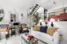 Open-concept interior featuring high ceilings, a floating staircase with glass railings, polished tile flooring, and integrated display shelving