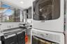 Laundry area featuring a stacked washer and dryer unit, built-in surface counter, metal wire shelving, and a window with horizontal blinds