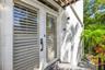 Exterior entrance featuring double glass-paneled doors with integrated horizontal louvers, a transom window, matte black hardware, and an overhead woo
