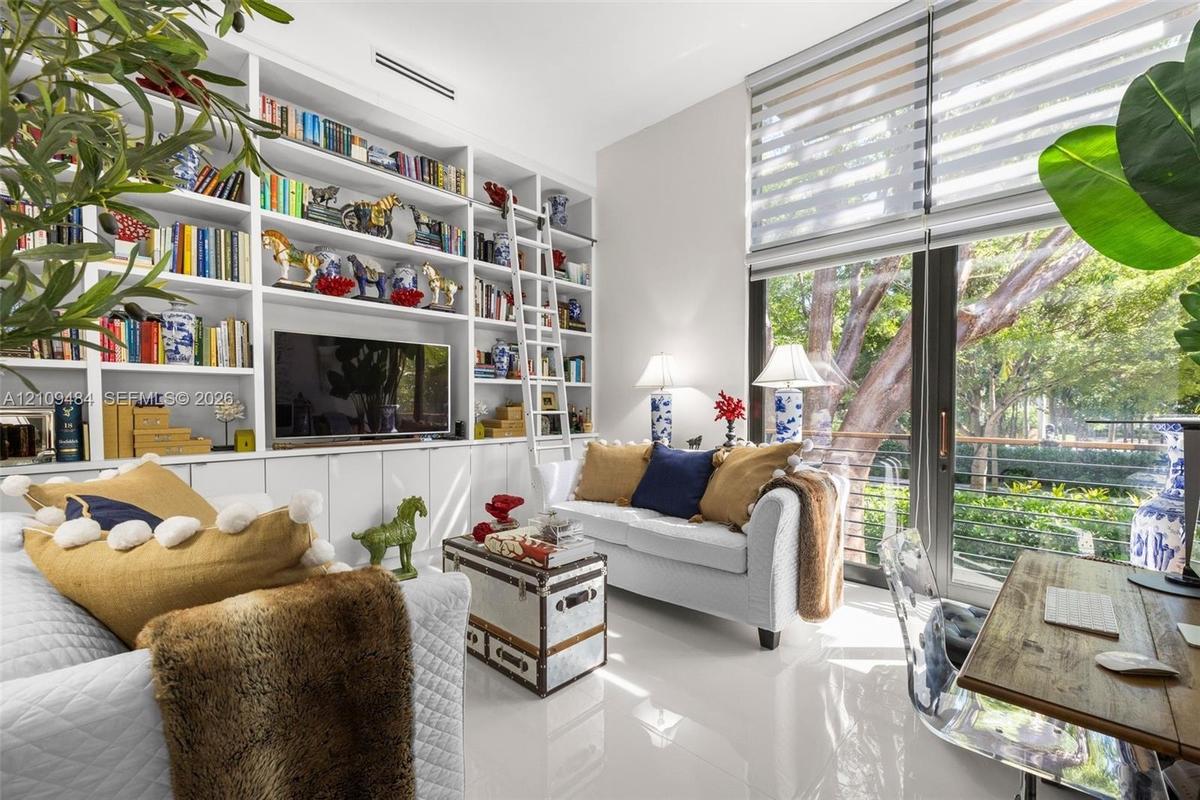 Full-height custom built-in cabinetry featuring integrated shelving, a rolling library ladder, and lower closed storage cabinets