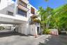 Contemporary multi-level exterior featuring white textured stucco, wood-slat window awnings, elevated balcony with black metal railing, and covered gr