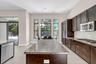 Gourmet kitchen featuring rich wood cabinetry, stainless steel appliances including a built-in microwave, granite countertops, and a substantial cente