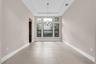 Bright, open room featuring soaring ceilings with recessed lighting, large multi-pane windows flooding the space with natural light, and neutral tile 