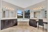 Spacious bathroom featuring a corner soaking tub, dual dark wood vanities with light countertops, a separate vanity area, large mirrors, and tile floo