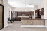 Open-concept kitchen and dining area featuring dark wood cabinetry, stainless steel appliances, a large island with wood-finish base, pendant lighting