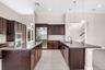 Expansive kitchen featuring dual islands with granite countertops, rich wood cabinetry, stainless steel appliances, and tile flooring