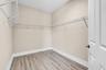 Interior closet featuring wood-finish flooring, white wire shelving, baseboard molding, and a paneled door