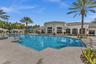 Resort-style pool area featuring a large swimming pool, surrounding patio, and a clubhouse with architectural columns