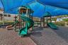 Expansive recreational area featuring dual spiral tube slides with elevated platforms, ground-level play structures, and engineered wood-fiber surfaci