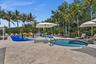 Outdoor amenity area featuring a splash pad with various water features, a circular spa with metal handrail, and multiple lounge chairs