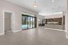 Spacious open-concept living area featuring polished tile flooring, recessed ceiling lighting, and a wood-finish kitchen with integrated appliances