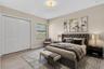 Spacious primary bedroom featuring a tufted upholstered headboard, wood-finish flooring, and recessed ceiling lighting
