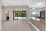 Open-concept living space featuring expansive tile flooring, pendant lighting, and abundant natural light from floor-to-ceiling sliding glass doors an