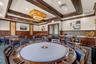 Spacious common area featuring a large round gaming table, multiple dining tables, wood-finish wall paneling, and built-in cabinetry with countertops