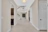 Bright two-story foyer featuring soaring ceilings, a curved staircase with white railings, neutral tile flooring throughout, and abundant natural ligh