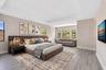 Spacious bedroom featuring light wood-finish flooring and a tray ceiling