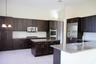 Kitchen featuring dark wood cabinetry, light-toned tile flooring, stainless steel appliances, granite countertops, and a central island