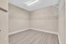 Spacious walk-in closet featuring pristine wood-finish flooring, neutral painted walls, and extensive wire shelving systems throughout