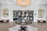 Spacious entry foyer featuring wood-finish flooring, a contemporary chandelier, crown molding, and a central round glass-top table