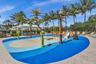 Vibrant splash pad featuring multiple water play structures, a small slide, and a durable blue and tan surface