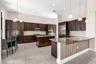 Gourmet kitchen featuring dark wood cabinetry, stainless steel appliances, and a large center island with wood-finish base and granite countertop