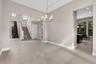Spacious main living area featuring large format tile flooring, a contemporary chandelier, and a prominent staircase with dark railings