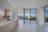 Kitchen featuring wood-finish cabinetry, stone countertops, built-in double ovens, and expansive floor-to-ceiling glass panel doors opening to a wrap-