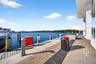 Waterfront bulkhead featuring herringbone-patterned brick pavers, concrete pier edging, and wood pilings