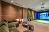 Wood-paneled accent wall, built-in projector system, integrated golf simulator screen, recessed ceiling lighting, and wall-to-wall carpeting