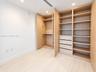 Custom built-in closet featuring light wood-finish shelving, hanging rods, and integrated drawers with recessed lighting and light wood-finish floorin