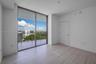 Floor-to-ceiling glass sliding doors, private balcony, wood-finish flooring, and neutral wall palette