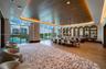 Custom wood-plank ceiling with integrated cove lighting, floor-to-ceiling glass paneling, built-in arched display shelving, and wood-finish flooring
