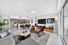 Open-concept interior featuring light-toned flooring, modern kitchen cabinetry with a central island, recessed lighting, and floor-to-ceiling glass sl