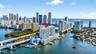 Aerial perspective of a high-rise residential building situated on the waterfront, featuring a private marina and balconies with glass railings