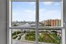 Oversized picture windows with white frames featuring panoramic exposure of the waterway, urban skyline, and surrounding landscape