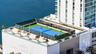 Rooftop tennis court featuring professional-grade blue surfacing, protective perimeter netting, integrated lighting, and decorative planters